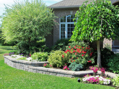 Landscape design with multiple levels and stone retaining wall for flower beds.